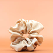Afro Scrunchie Satin Beige Vorderansicht vor einem braunen Hintergrund