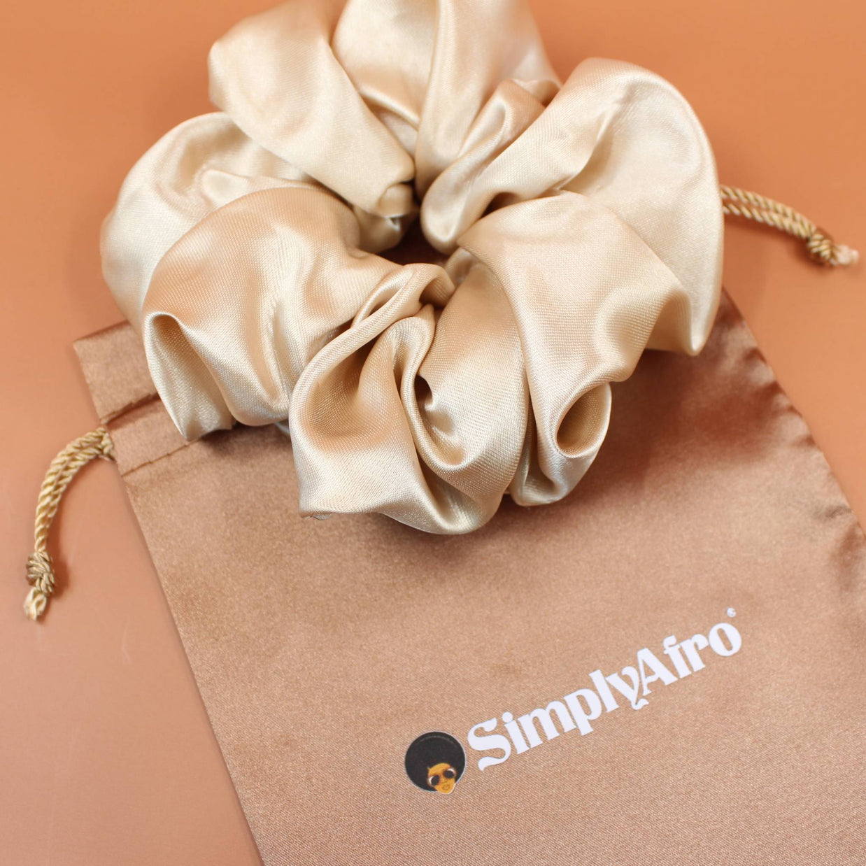 Afro Scrunchie Satin Beige liegend auf einem braunen SimplyAfro Säckchen