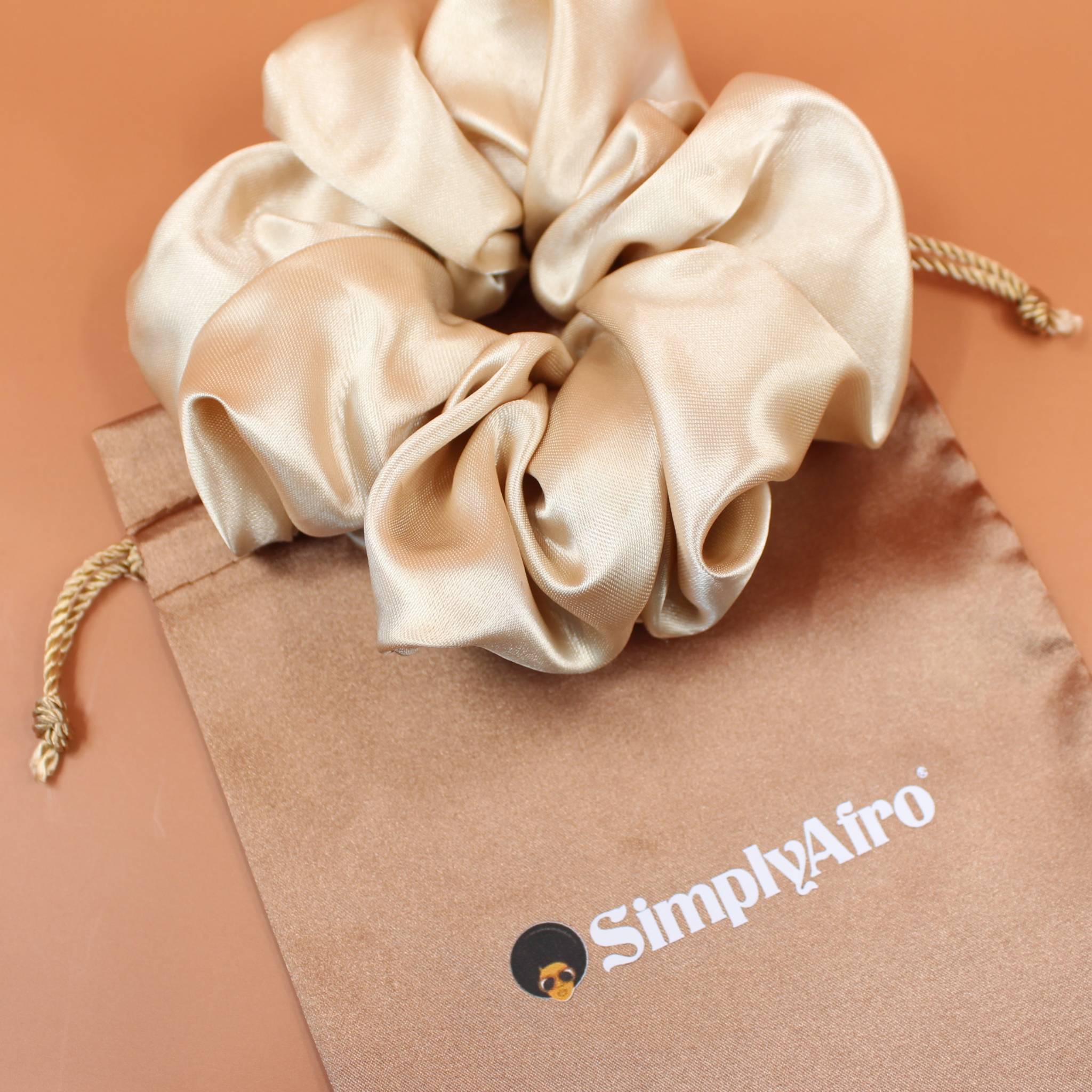 Afro Scrunchie Satin Beige liegend auf einem braunen SimplyAfro Säckchen