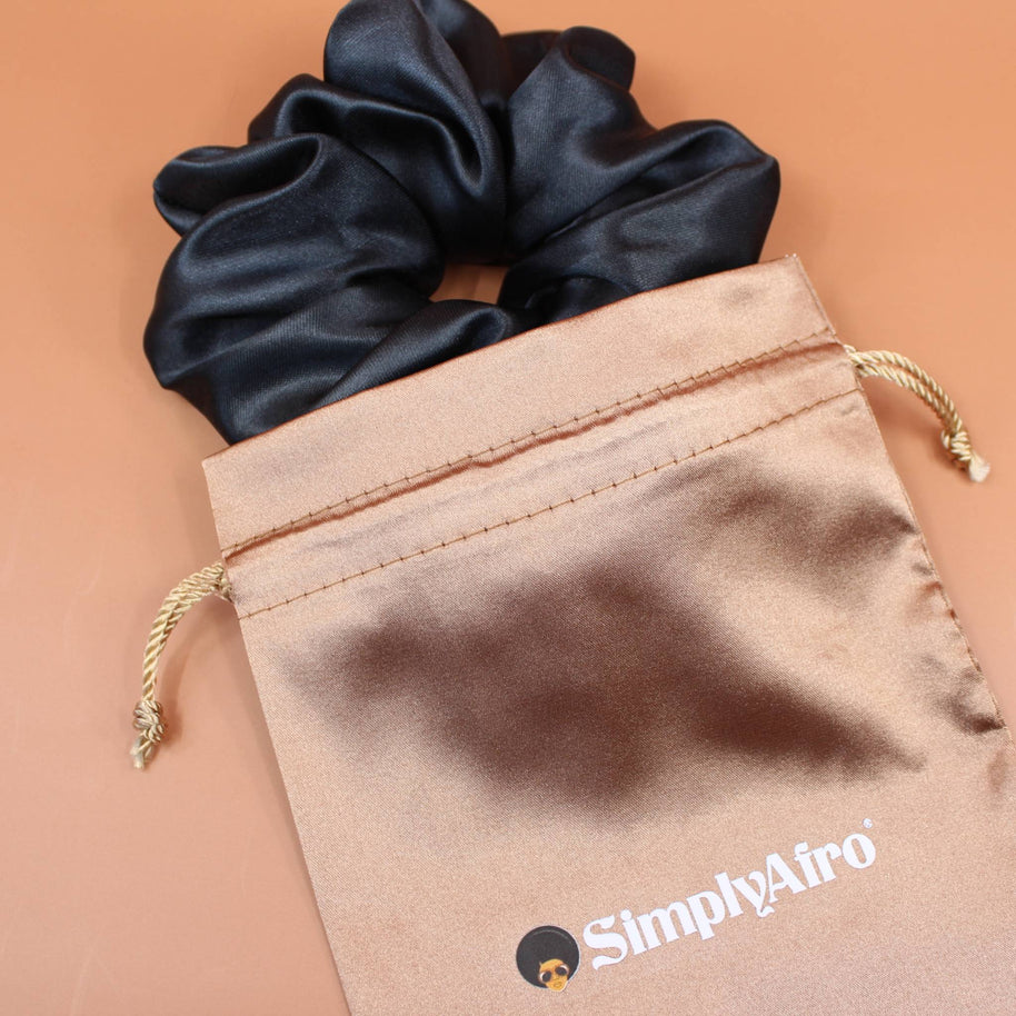 Afro Scrunchie Satin Schwarz liegend auf einem braunen SimplyAfro Säckchen