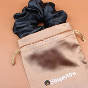 Afro Scrunchie Satin Schwarz liegend auf einem braunen SimplyAfro Säckchen