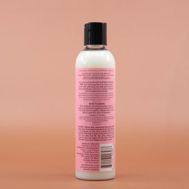 Das Haarpflegeprodukt CAMILLE ROSE Curl Love Moisture Milk 240ml in der Rückansichtt vor einem braun-orangen Hintergrund.