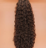 DREAM HAIR Ponytail Diborra Curly, Farbe 6 (mittelbraun) in der Vorderansicht vor einem braun-orangen Hintergrund.