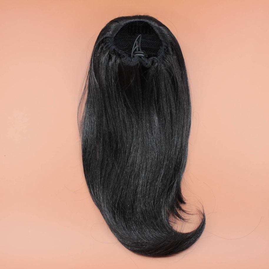 DREAM HAIR Ponytail Straight 14 inches, Farbe 1 (schwarz) in der Rückansicht vor einem braun-orangen Hintergrund.