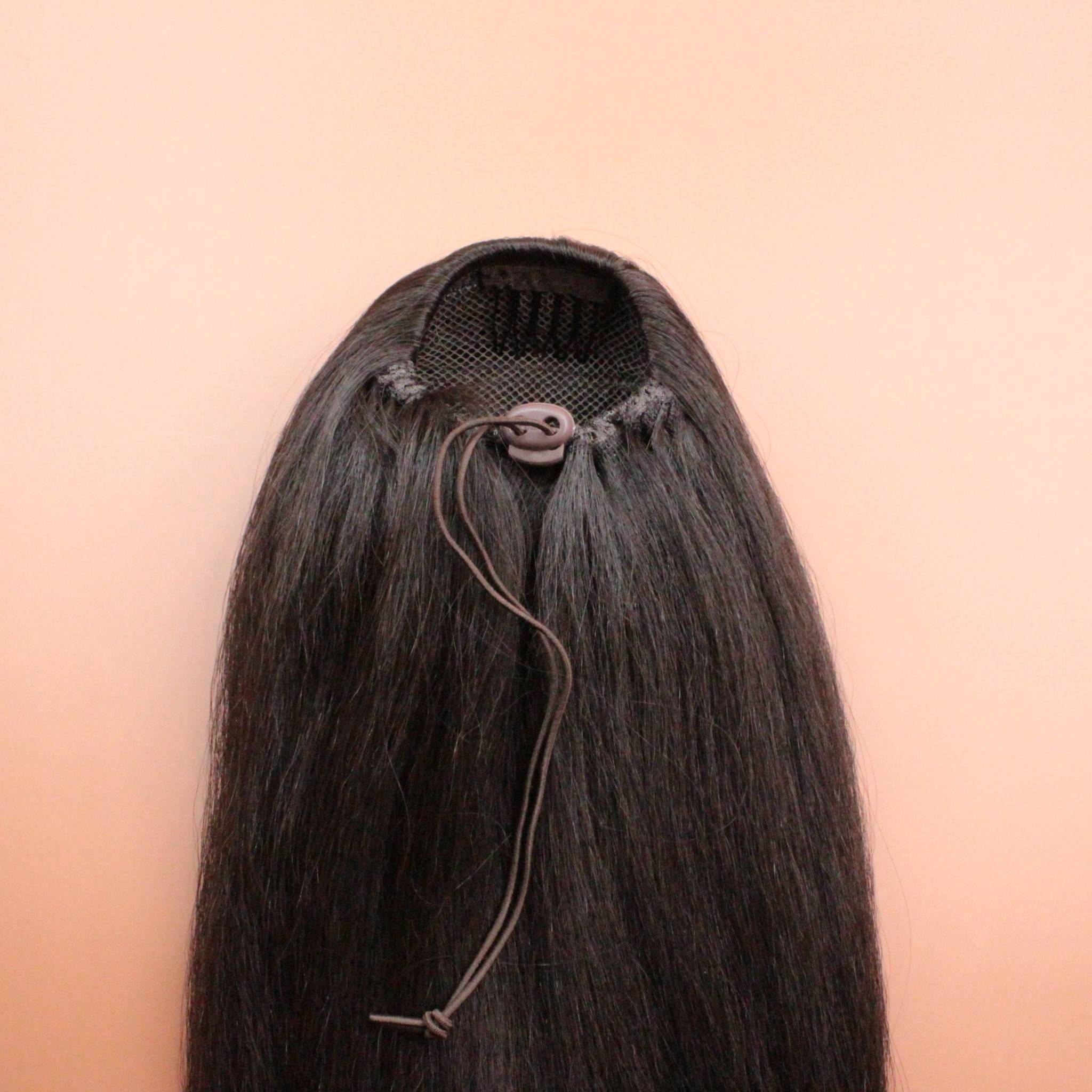 DREAM HAIR Ponytail Straight 30'', Farbe 4 (braun) in der Rückansicht vor einem braun-orangen Hintergrund.