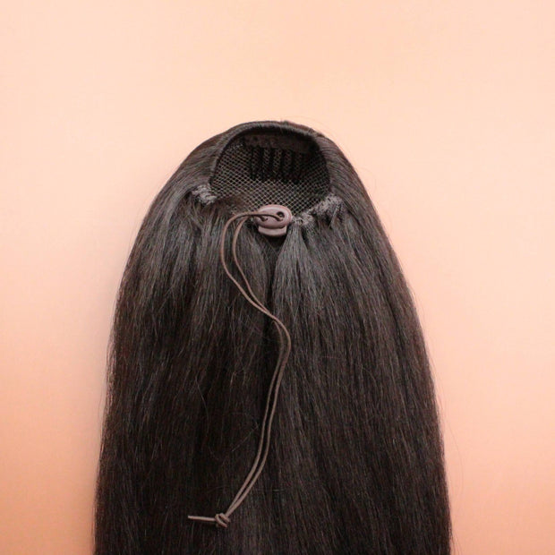 DREAM HAIR Ponytail Straight 30'', Farbe 4 (braun) in der Rückansicht vor einem braun-orangen Hintergrund.