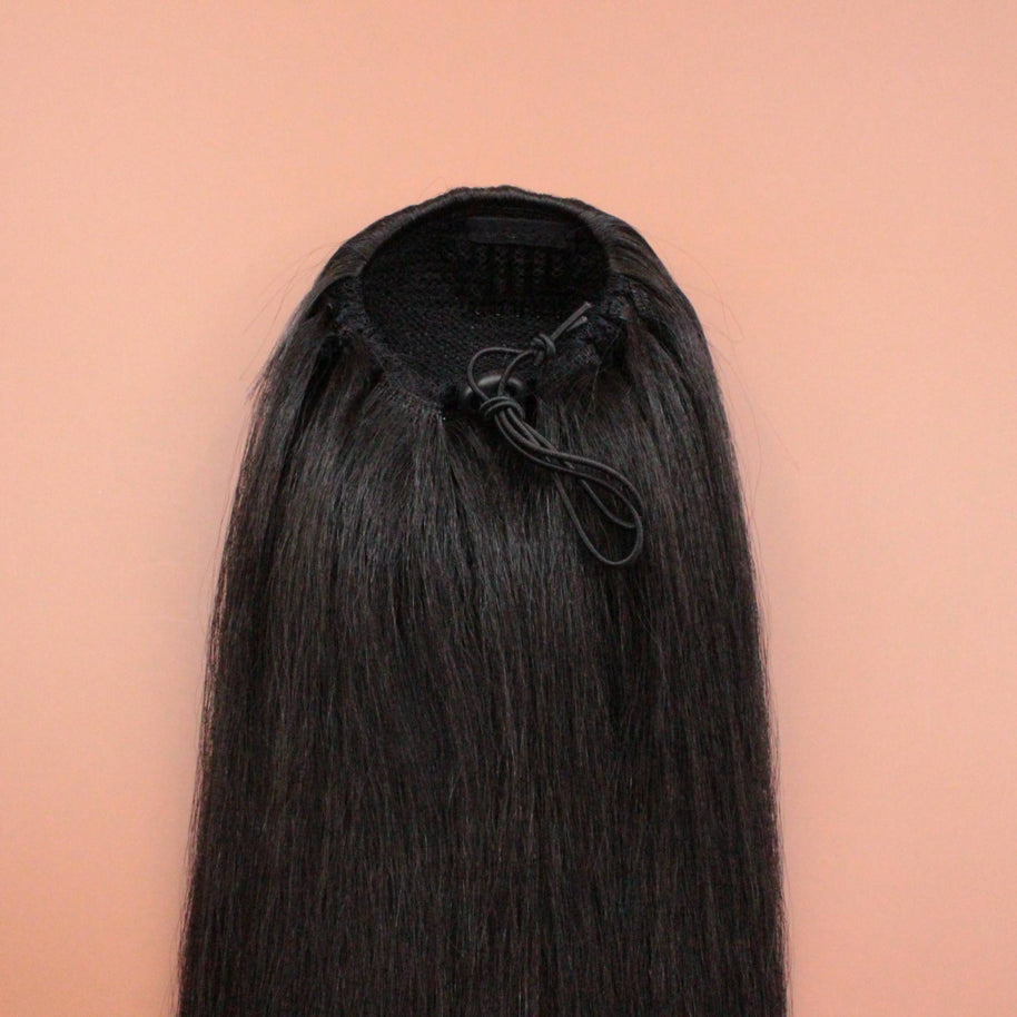 DREAM HAIR Ponytail Straight 30'', Farbe 2 (dunkelbraun) in der Rückansicht vor einem braun-orangen Hintergrund.
