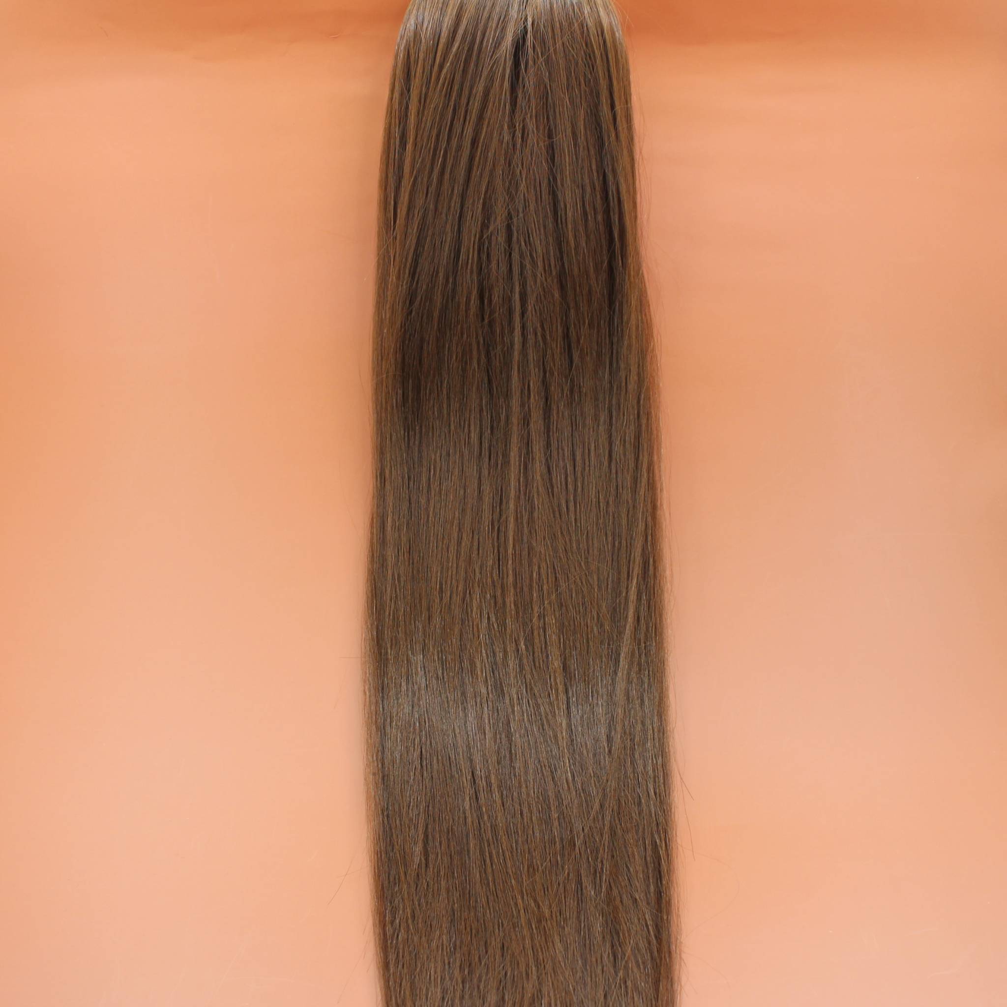 DREAM HAIR Ponytail Straight 30'', Farbe 8 (mittelbraun) in der Vorderansicht vor einem braun-orangen Hintergrund.