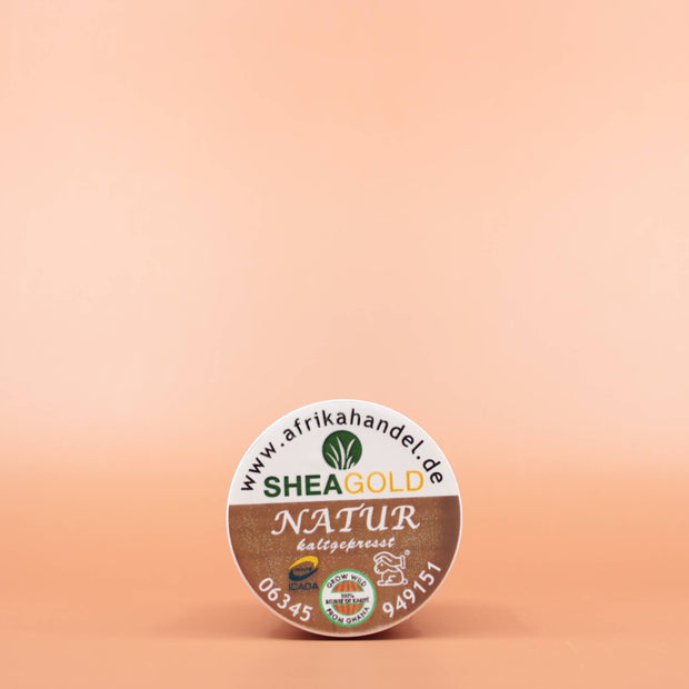 SHEA GOLD 100% Natural Fair Trade Bio Sheabutter 100ml in der Draufsicht vor einem braun-orangen Hintergrund
