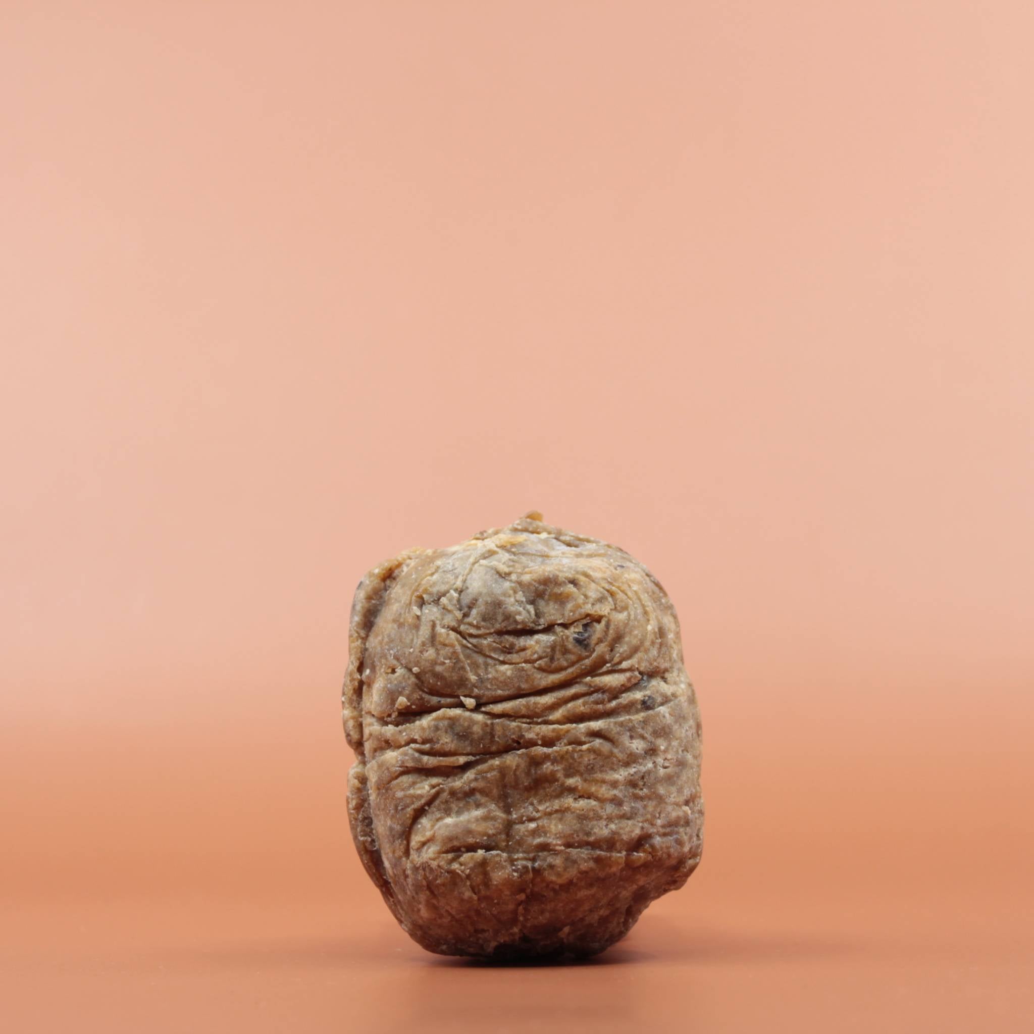Das Hautpflegeprodukt SHEA GOLD Black Soap 100g in der Vorderansicht vor einem braun-orangen Hintergrund.