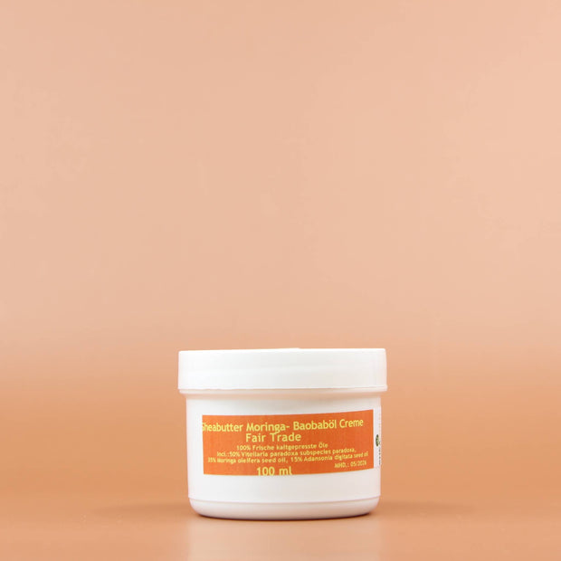 SHEA GOLD Moringa Baobab Sheabutter Creme 100ml Vorderansicht vor einem orange braunen Hintergrund 