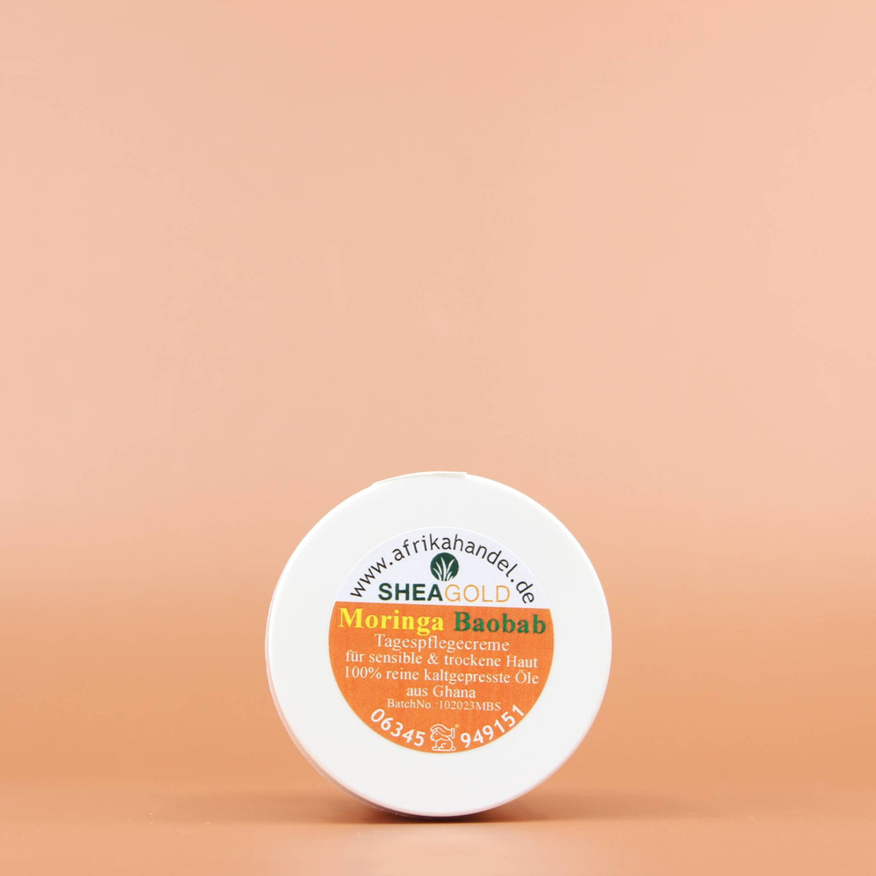 SHEA GOLD Moringa Baobab Sheabutter Creme 100ml Ansicht vom Deckel vor einem orange braunen Hintergrund 