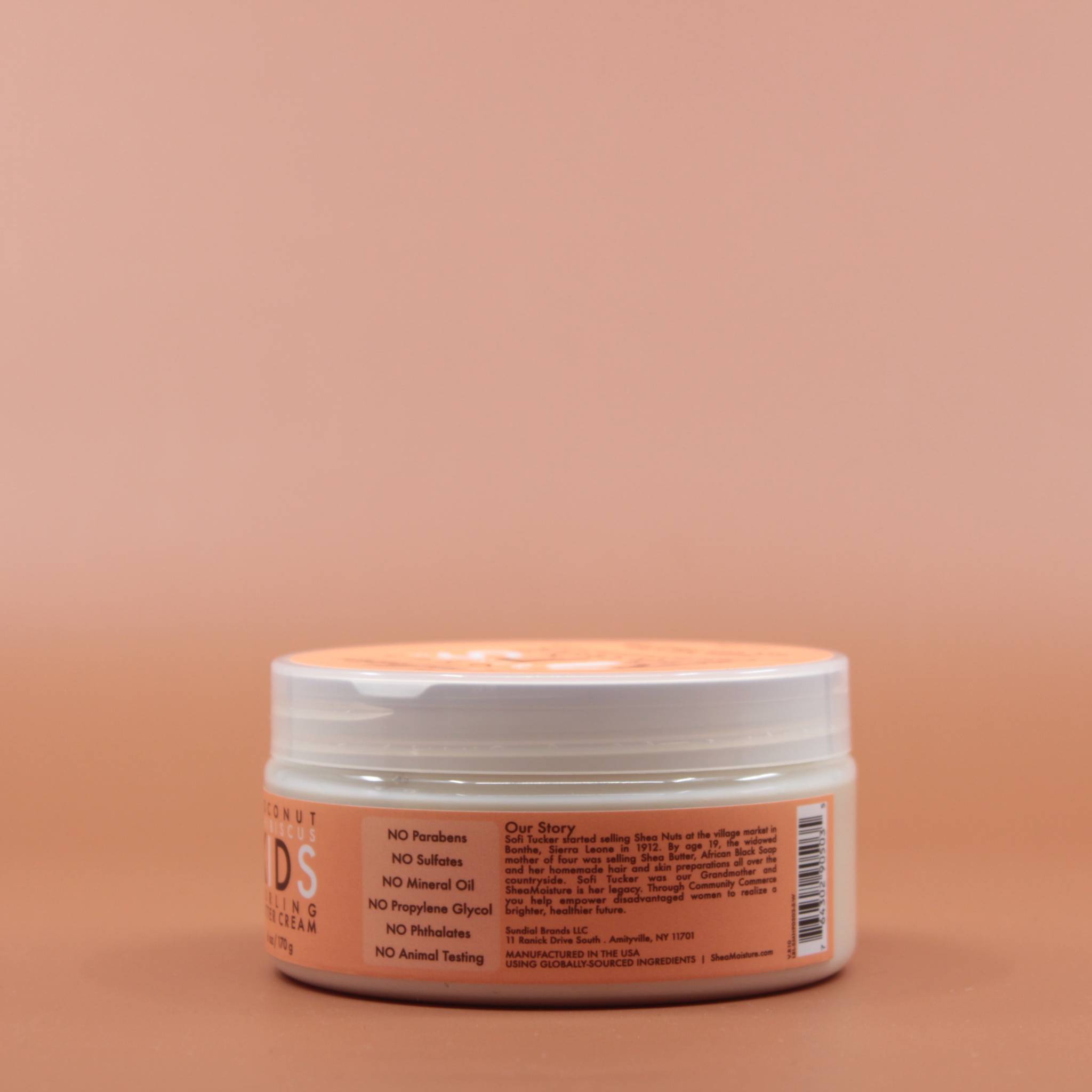 Das Kinder Haarpflegeprodukt SHEA MOISTURE Kids Curling Butter Cream 170g in der Seitenansicht (links) vor einem braun-orangen Hintergrund.