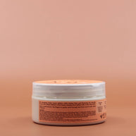 Das Kinder Haarpflegeprodukt SHEA MOISTURE Kids Curling Butter Cream 170g in der Rückansicht vor einem braun-orangen Hintergrund.